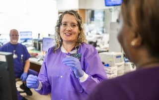 Two laboratory caregivers holding a conversation, while another caregiver looks on.