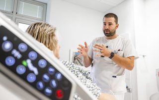 A nursing caregiver speaks with a patient in a hospital room.