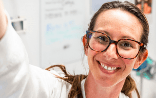 Smiling woman in lab coat working with laboratory equipment.
