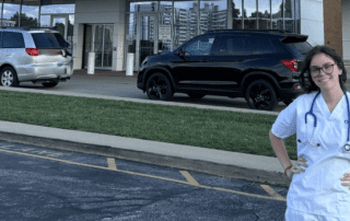 Nurse standing outside a medical facility smiling at the camera.