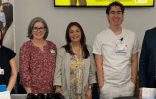 Group of healthcare professionals standing behind a recruitment table at a hospital event.