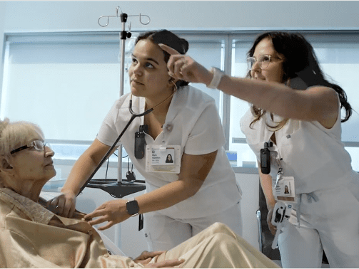 Two female nursing students caring for an elderly female patient