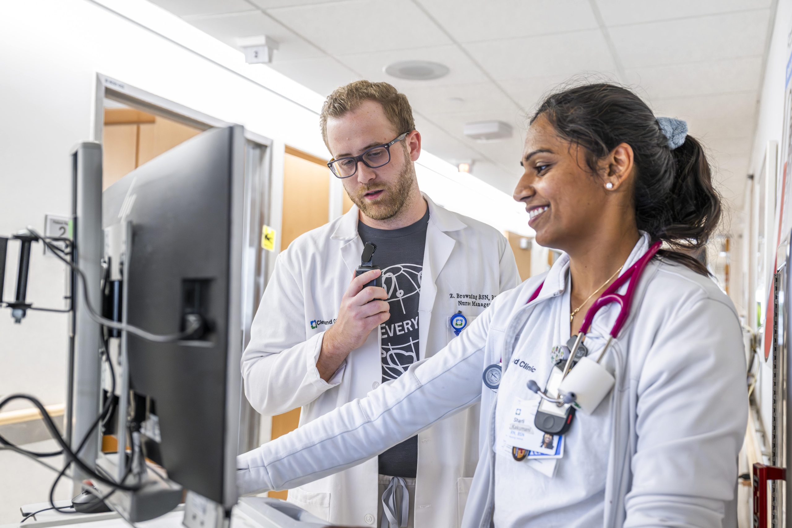Two medical Cleveland Clinic staff in white coats working together at a computer.