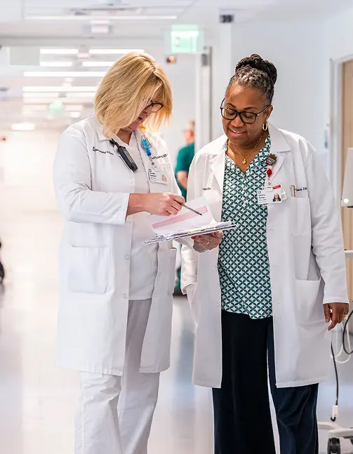 Two female nurses examining a patient's chart