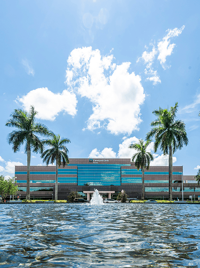 Exterior of a Cleveland Clinic hospital in Florida with palm trees and a fountain in front